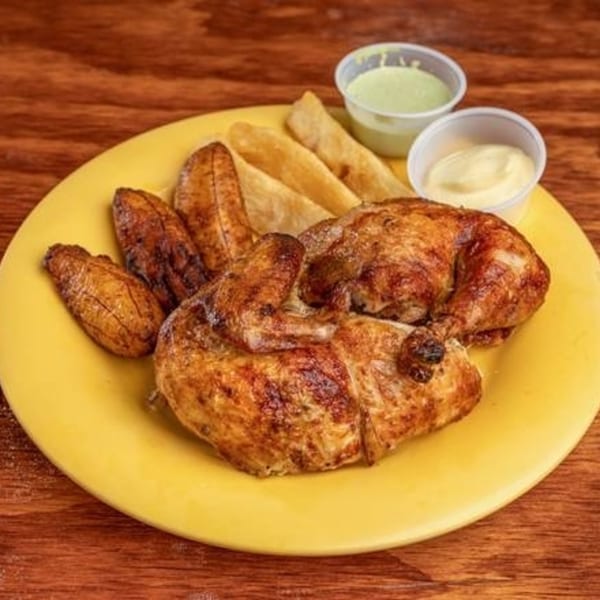 MMM Que Rico's roasted chicken with fried plantains, yuca fries, and two dipping sauces on a yellow plate.