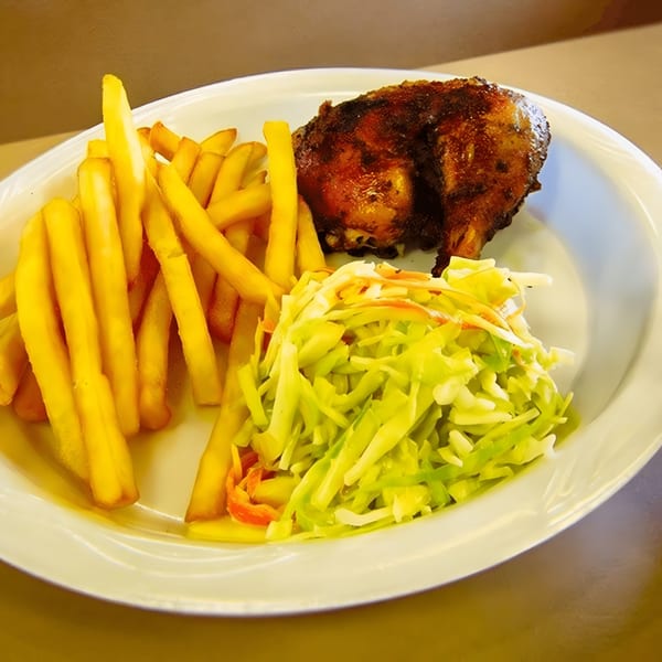MMM Que Rico's Latin-American dish with roasted chicken, golden fries, and fresh coleslaw on a white plate.