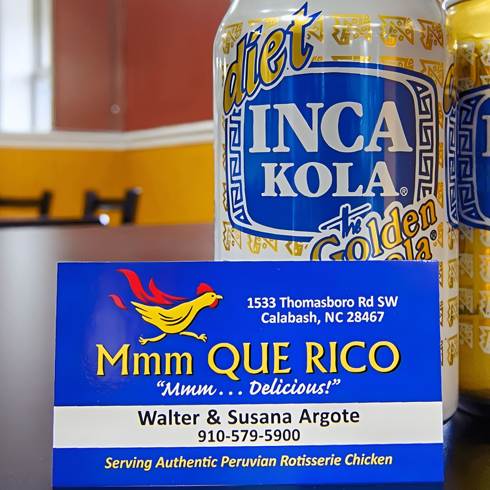 Mmm Que Rico business card in front of Diet Inca Kola cans, advertising Peruvian rotisserie chicken.